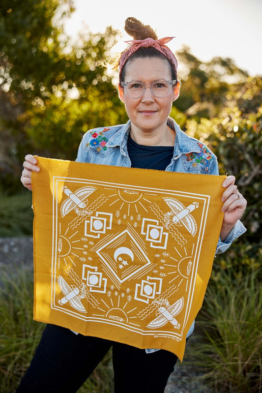 Picture of Megan Young holding a handmade yellow Campfire Co bandana