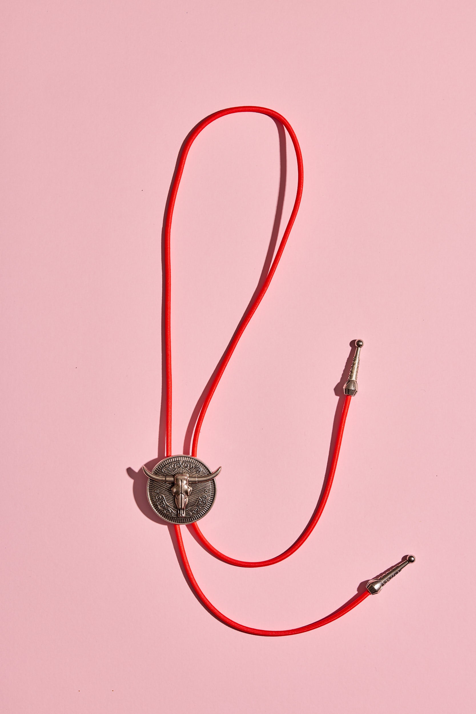 Handmade bolo tie with bright coloured cord and silver turquoise-look hardware, displayed on neutral background – western costume jewellery made in Australia