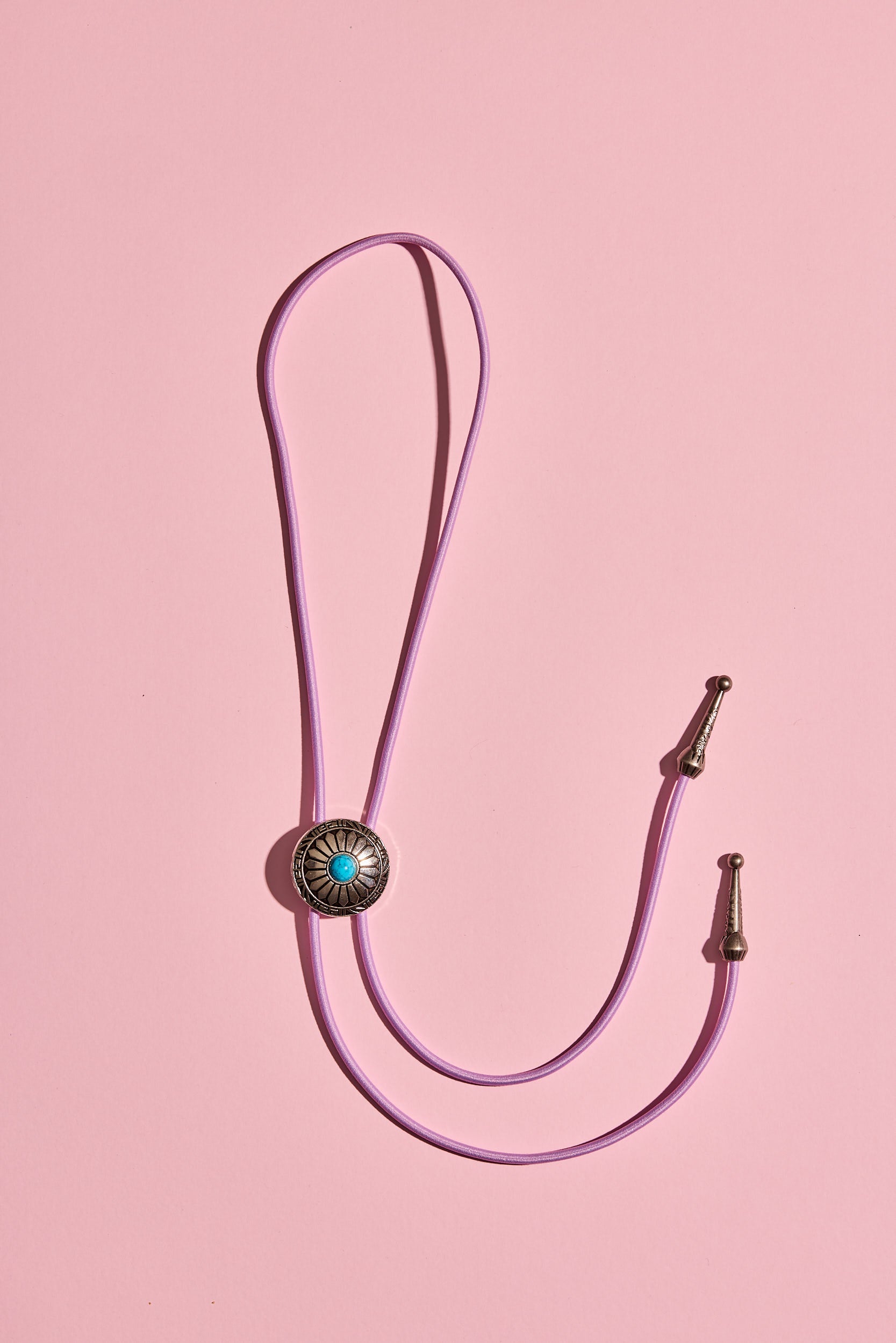 Handmade bolo tie with bright coloured cord and silver turquoise-look hardware, displayed on neutral background – western costume jewellery made in Australia