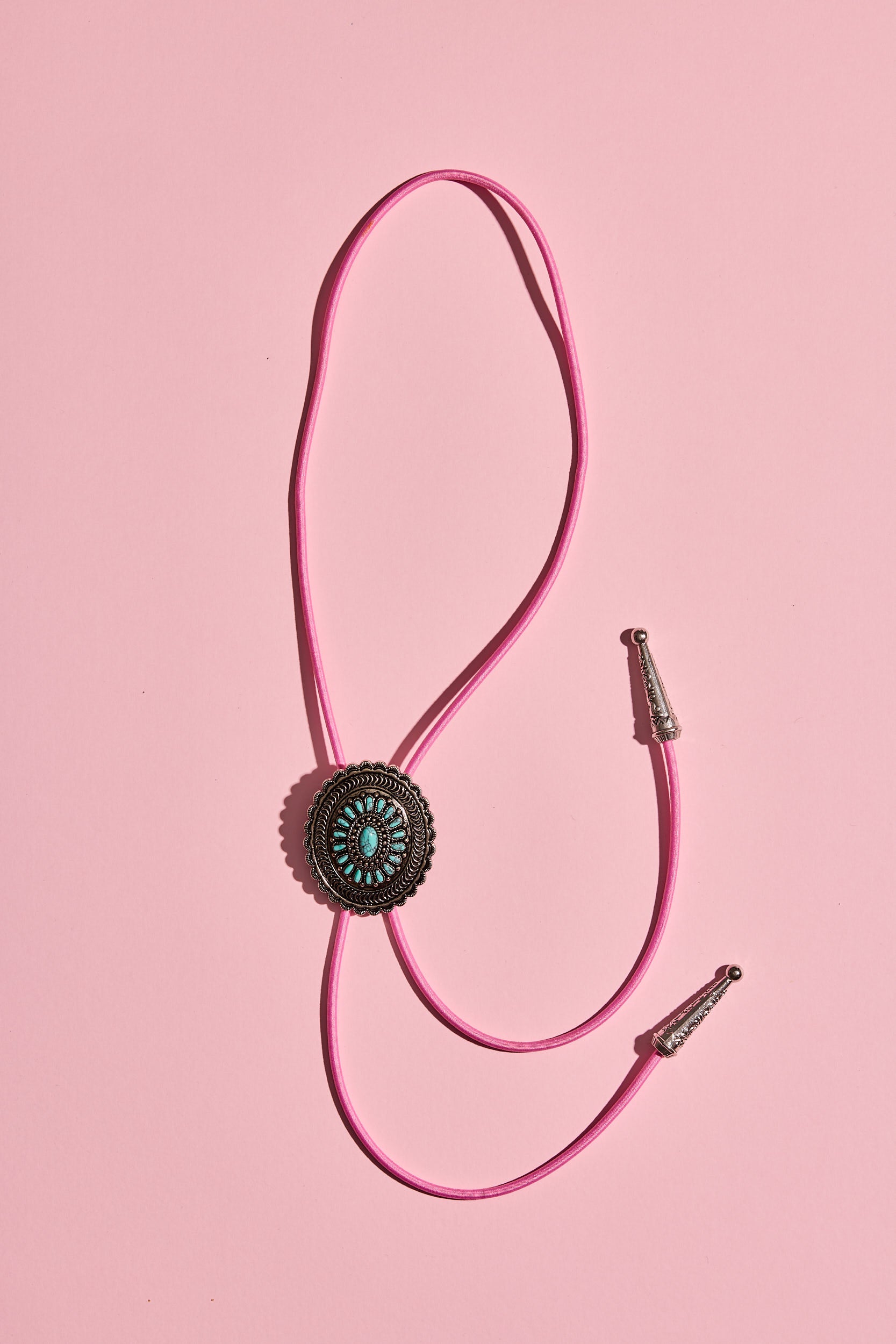 Handmade bolo tie with bright coloured cord and silver turquoise-look hardware, displayed on neutral background – western costume jewellery made in Australia