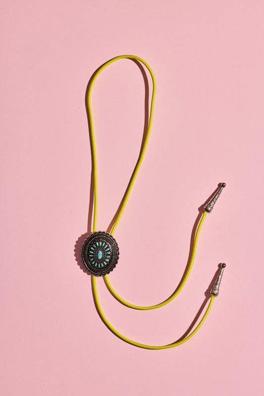 Handmade bolo tie with bright coloured cord and silver turquoise-look hardware, displayed on neutral background – western costume jewellery made in Australia