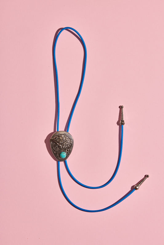 Handmade bolo tie with bright coloured cord and silver turquoise-look hardware, displayed on neutral background – western costume jewellery made in Australia