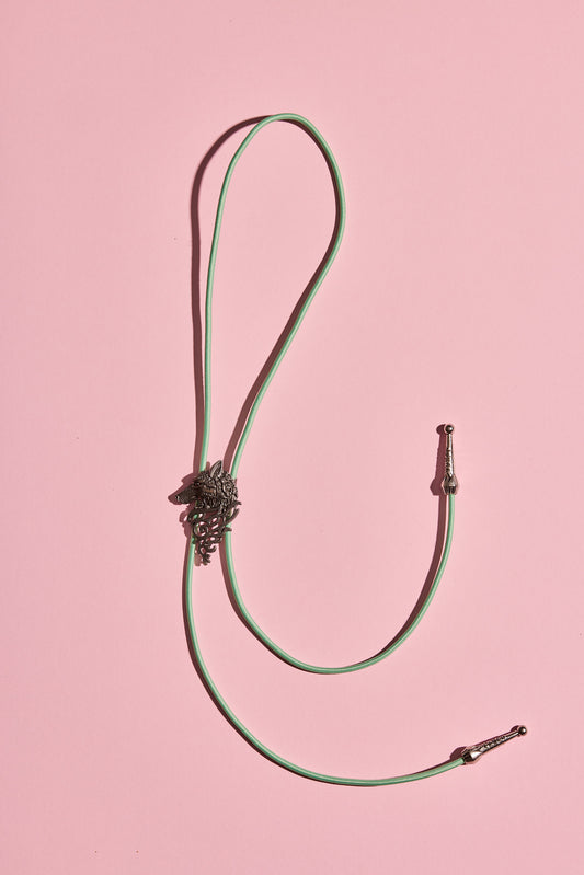 Handmade bolo tie with bright coloured cord and silver turquoise-look hardware, displayed on neutral background – western costume jewellery made in Australia