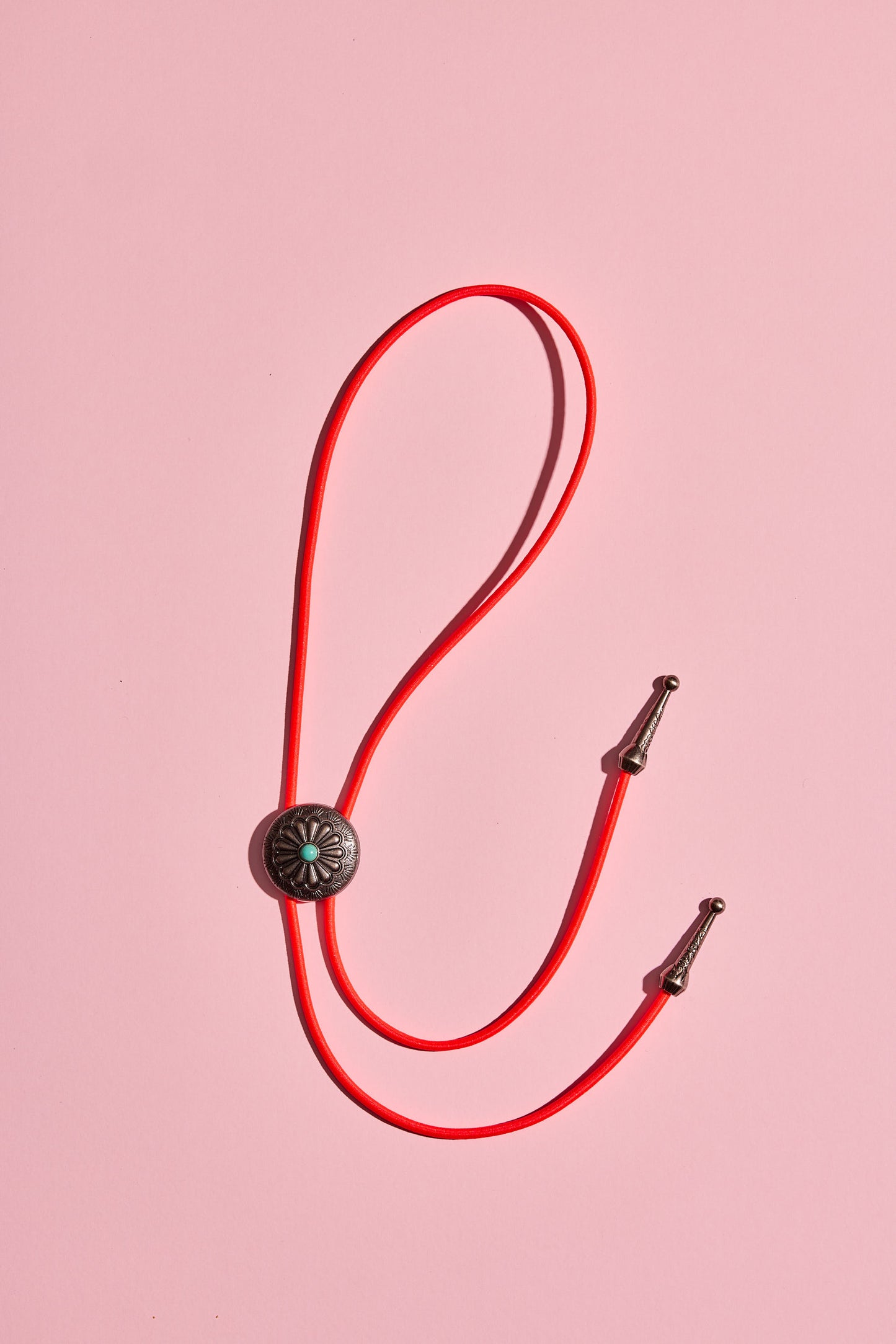 Handmade bolo tie with bright coloured cord and silver turquoise-look hardware, displayed on neutral background – western costume jewellery made in Australia