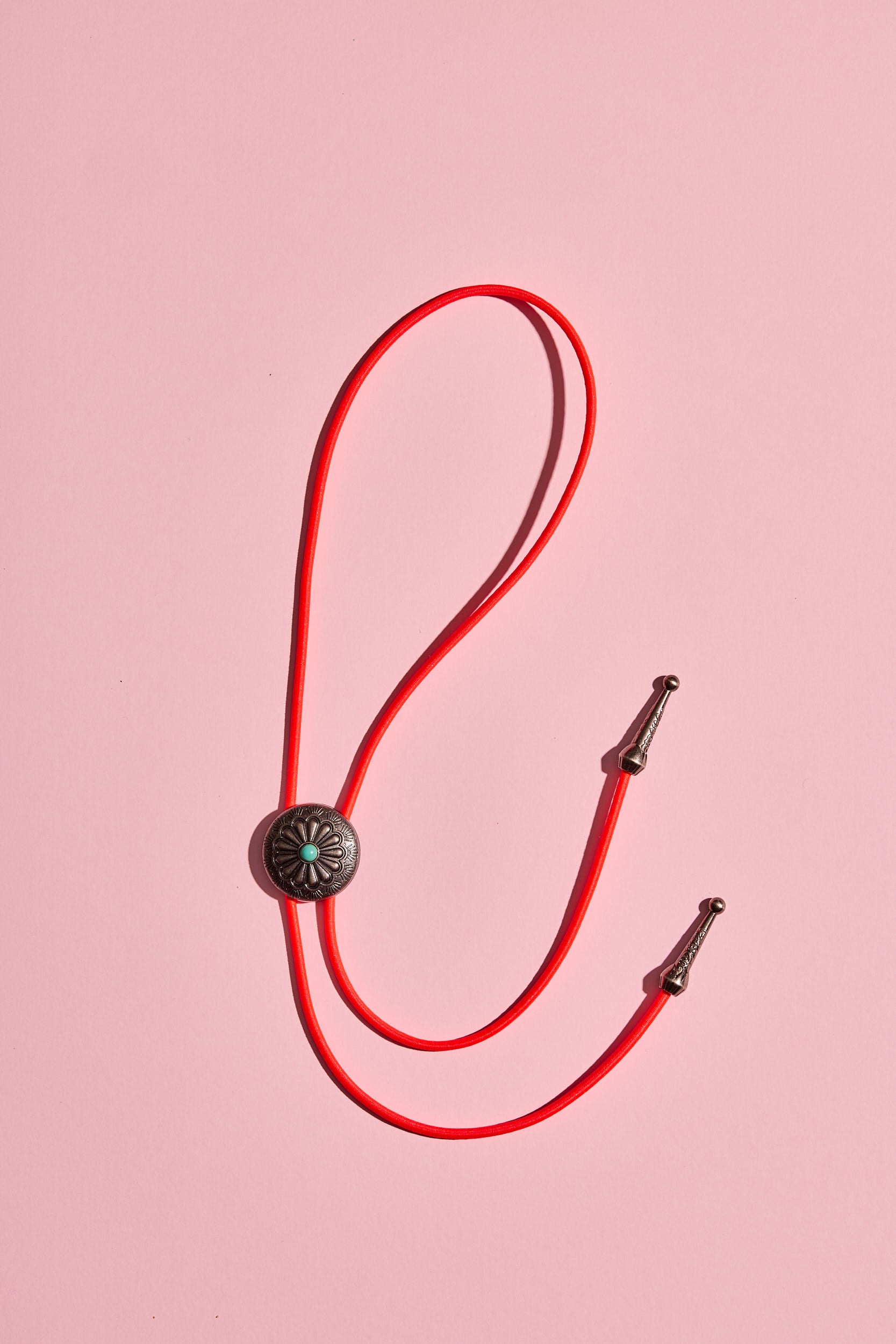 Handmade bolo tie with bright coloured cord and silver turquoise-look hardware, displayed on neutral background – western costume jewellery made in Australia