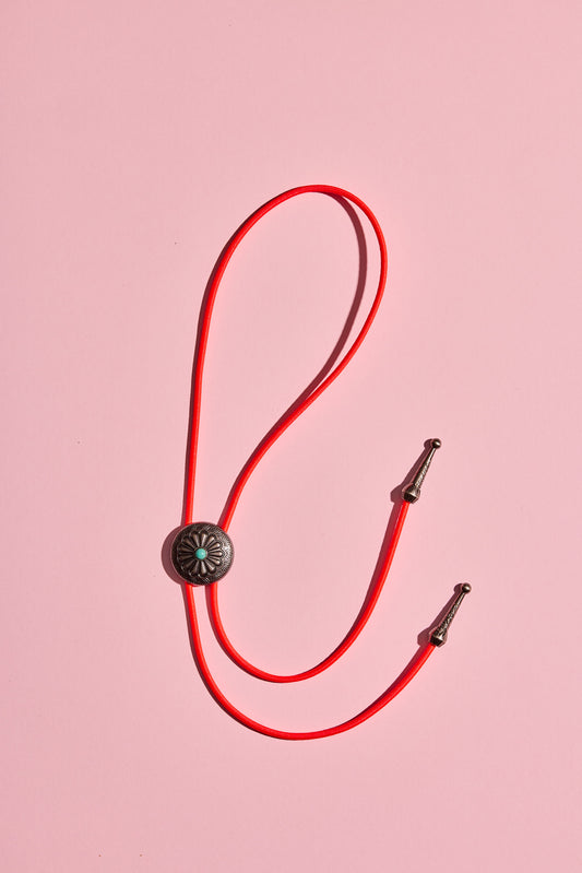 Handmade bolo tie with bright coloured cord and silver turquoise-look hardware, displayed on neutral background – western costume jewellery made in Australia